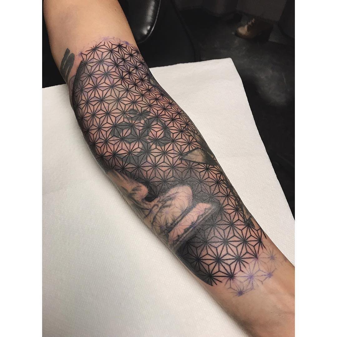 Geometric tattoo of interlocking circles and triangles covering a person's forearm