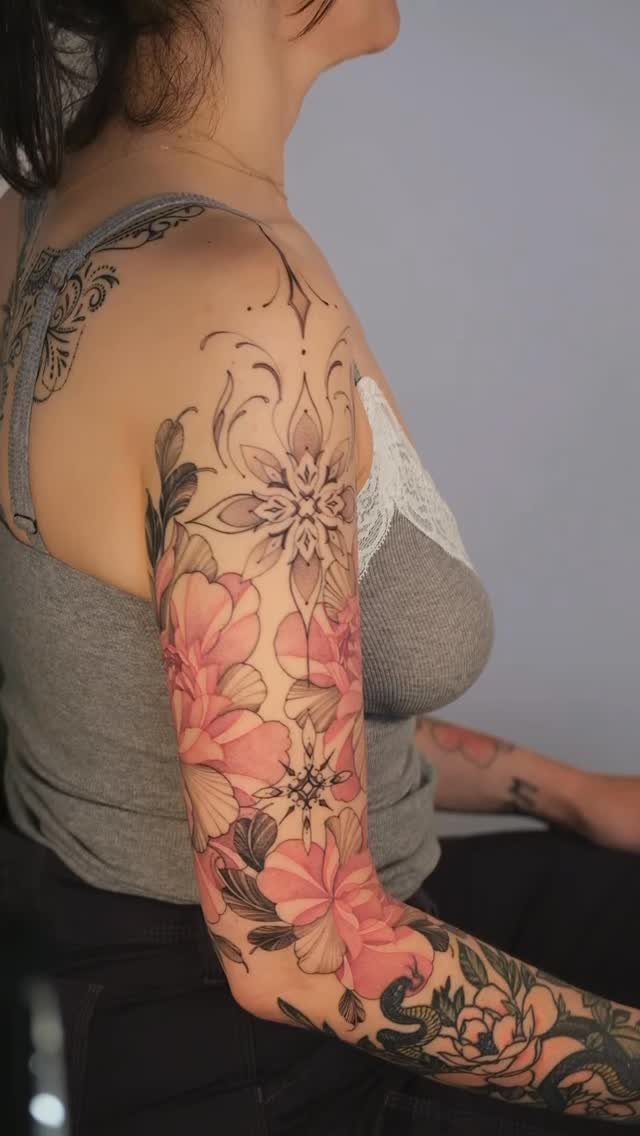 Tattoo on a woman's arm combining pink floral blooms with a geometric mandala design.