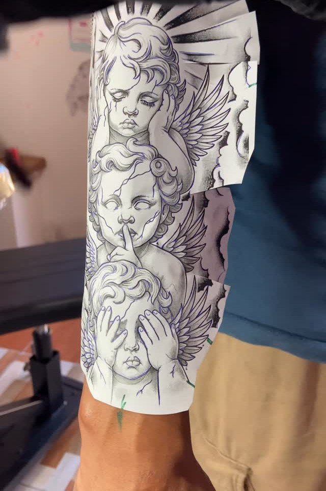Forearm tattoo stencil featuring three cherubs representing see, hear, and speak no evil.
