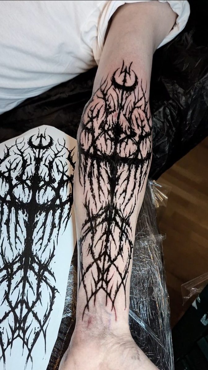 Forearm with a full length black ink tattoo stencil and matching paper design