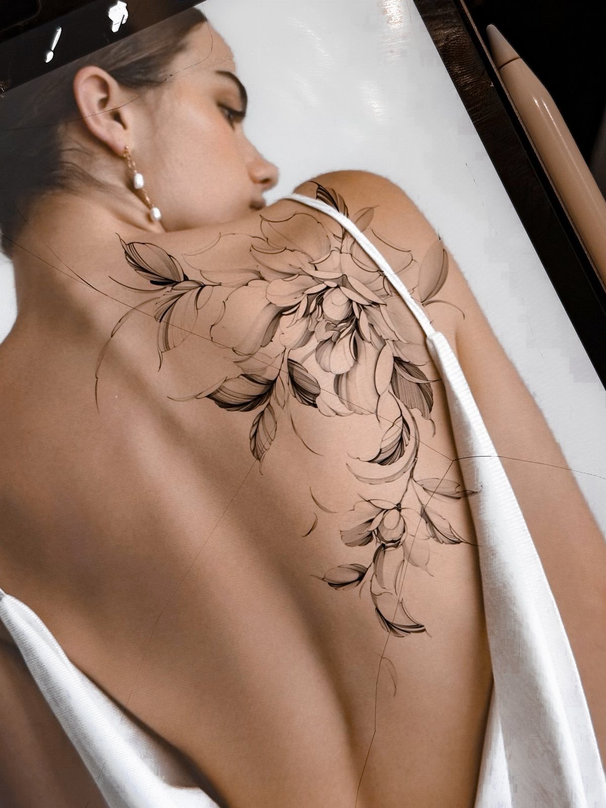 Floral black ink tattoo design on a woman's upper back and shoulder
