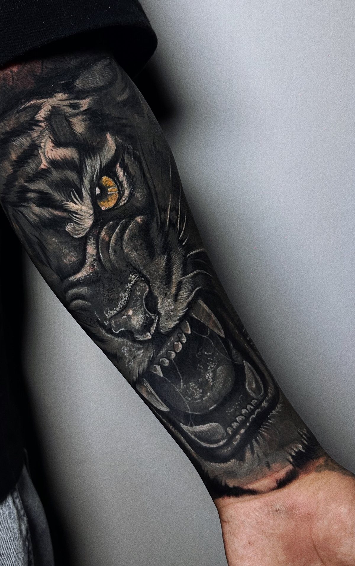 Black panther tattoo with yellow eye covering a person's entire arm sleeve.