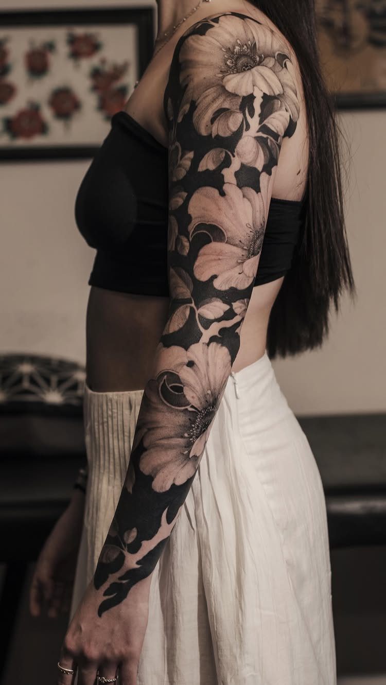 Full sleeve tattoo of large floral designs covering a person's entire arm.