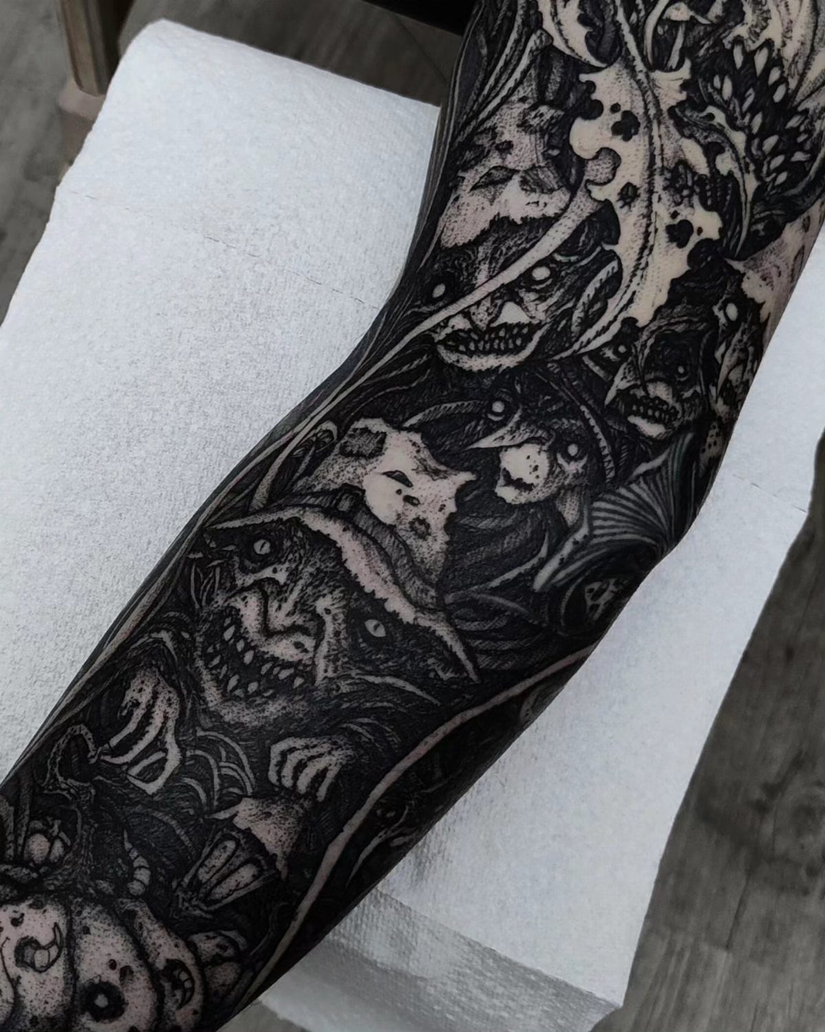 Full sleeve tattoo with dark surreal monsters covering an entire arm.