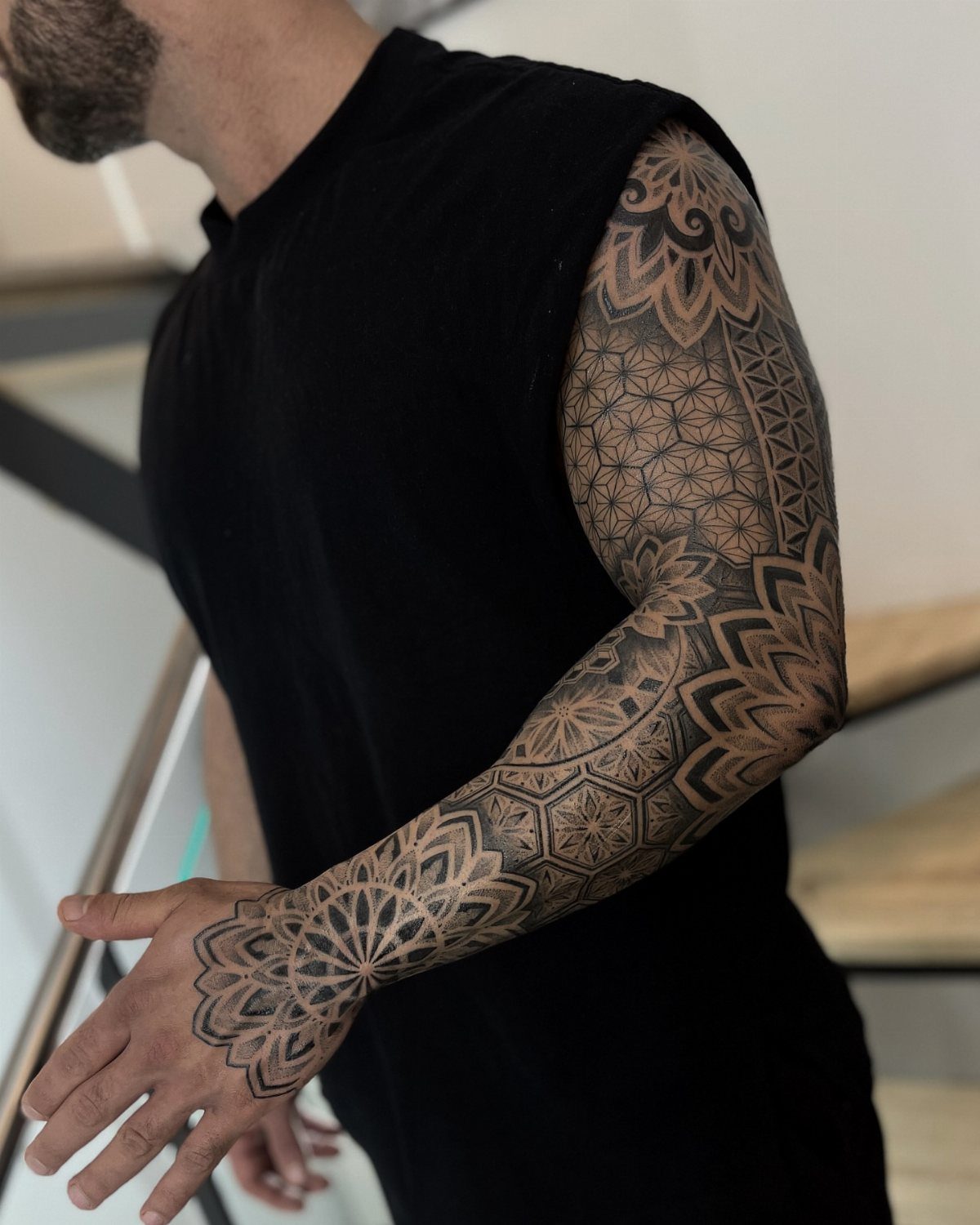 Full sleeve tattoo with geometric and mandala patterns on a man's arm