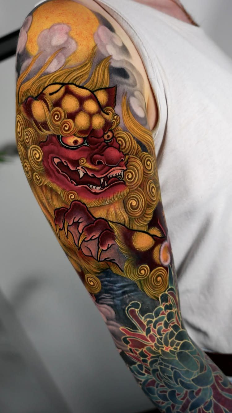Full sleeve tattoo of a red and gold mythical lion with floral details.