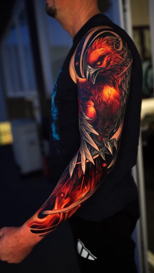 Full sleeve tattoo of a red phoenix on a man's arm