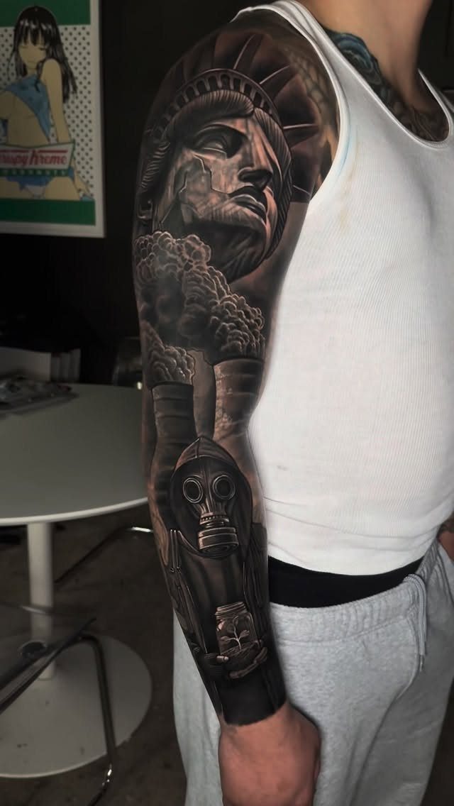 Full sleeve black and grey tattoo featuring Statue of Liberty and a gas mask.