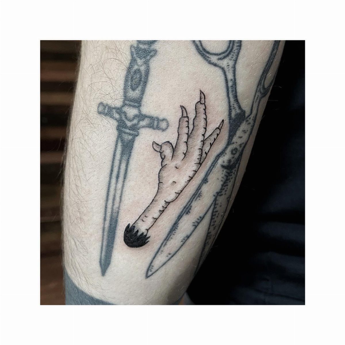 Bird foot tattoo acting as a gap filler between a dagger and scissors.