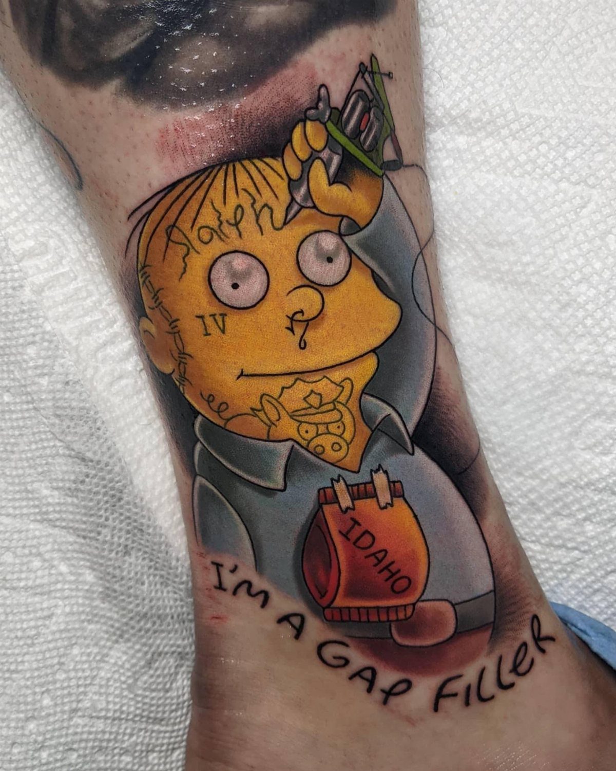 Cartoon character tattoo holding a tattoo machine with Idaho potato sack on skin
