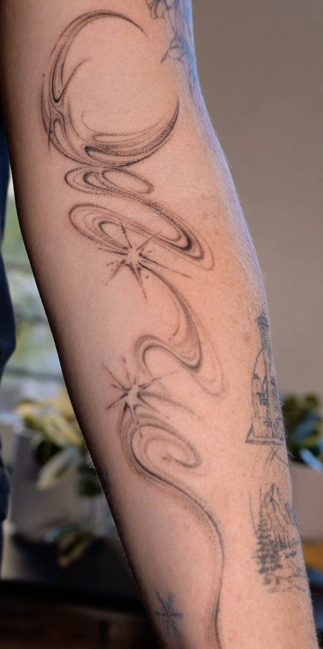 Tattoo on an arm with swirling black lines and small four-pointed stars.