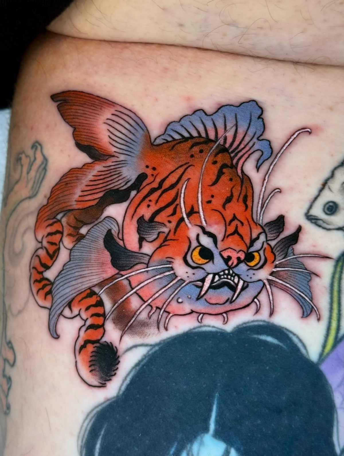 Traditional style tattoo of an angry orange striped fish with sharp teeth.