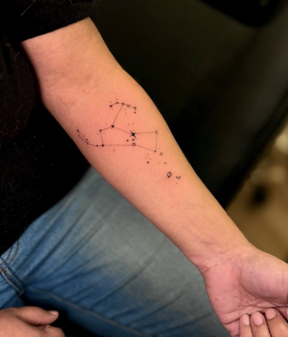Constellation tattoo with stars and a crescent moon on a person's inner forearm.