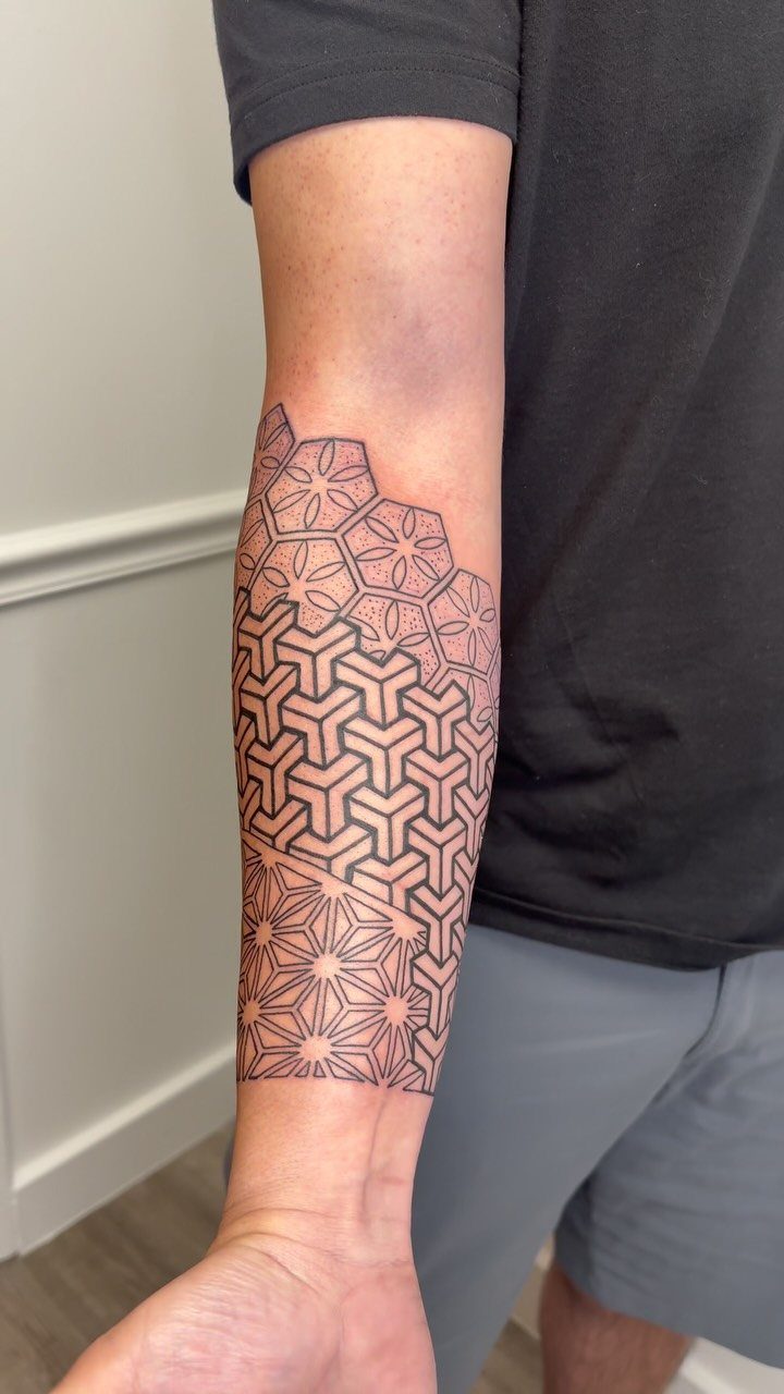 Geometric black ink tattoo with interlocking patterns on a person's forearm