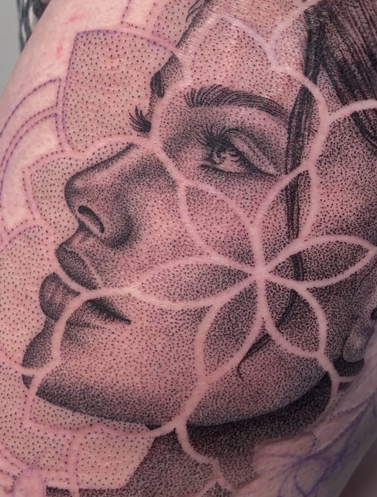 Woman's face tattoo created with intricate dot work and floral outlines on skin