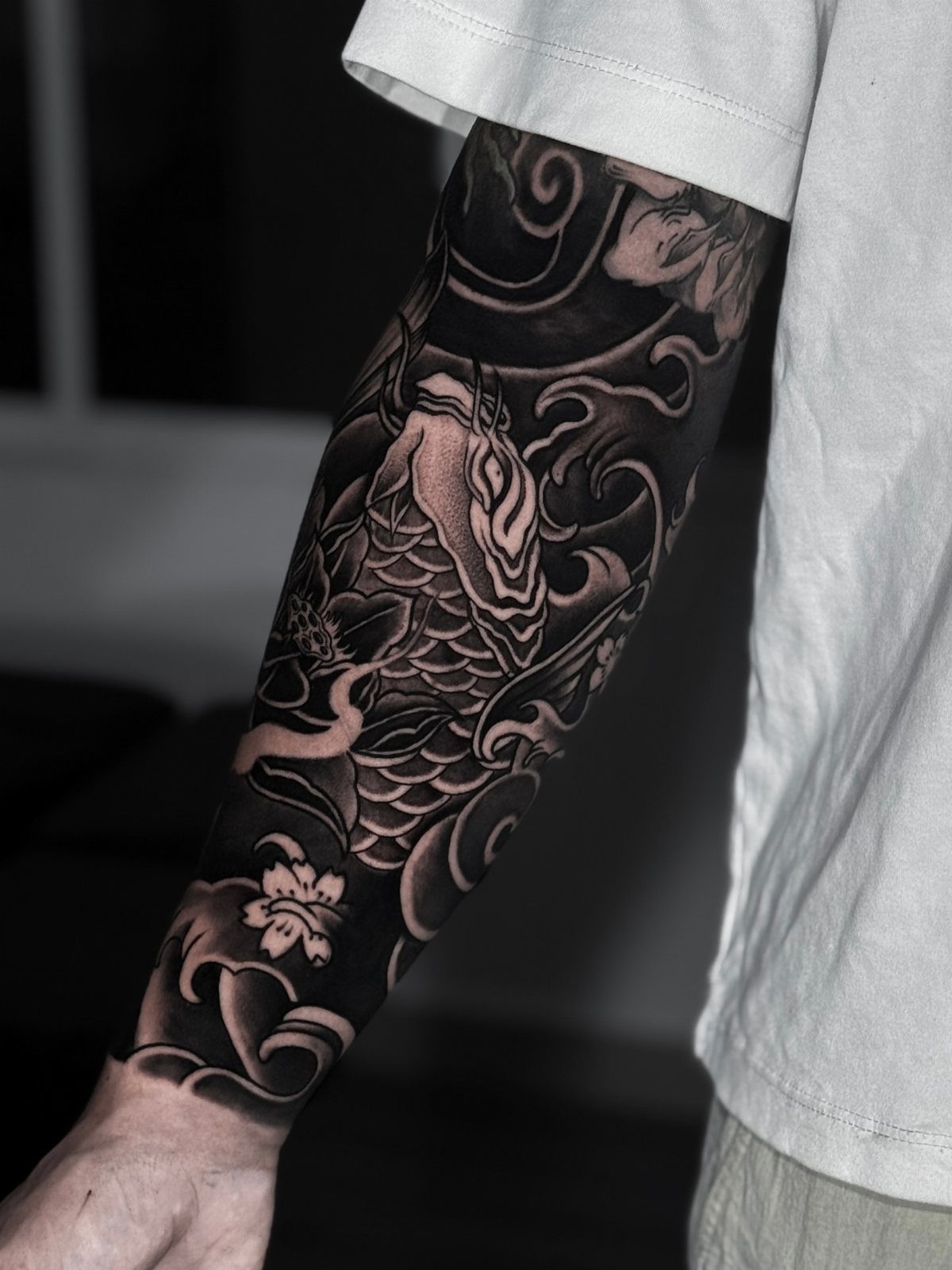 Koi fish tattoo on an arm surrounded by traditional Japanese wave patterns.