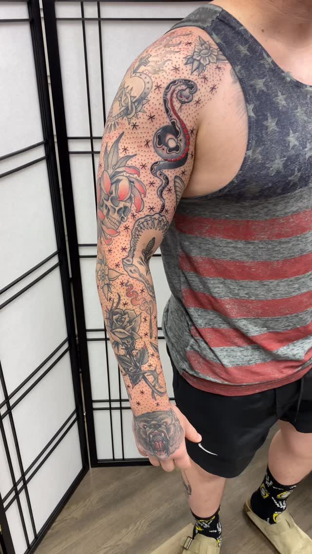 Tattooed arm sleeve with small black stars used as fillers between larger designs