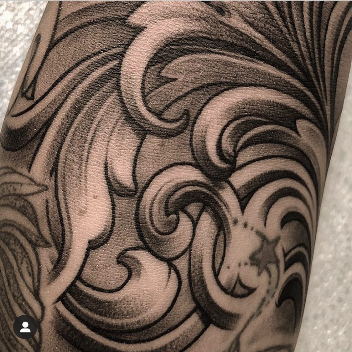 Curvy black and grey swirl tattoo patterns on a person's skin.