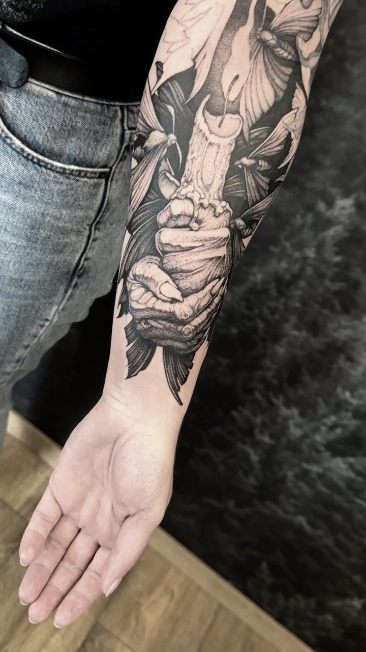 Forearm tattoo of a hand holding a melting candle with dark gothic elements.