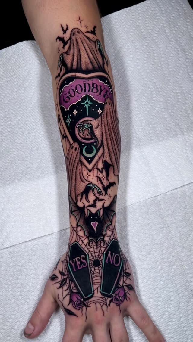 Tattoo on forearm and hand featuring a draped ghost, coffins, and bats.