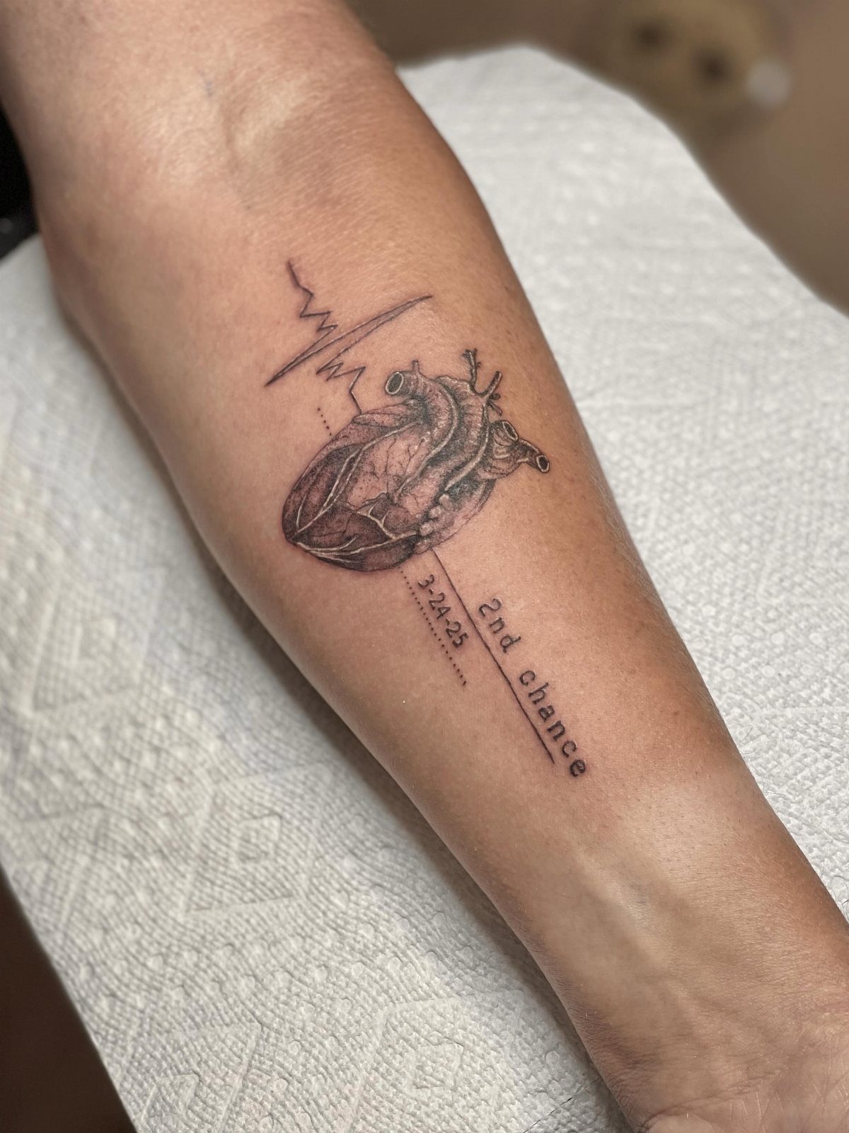 Anatomical heart tattoo with heartbeat line and 2nd chance text on a forearm.