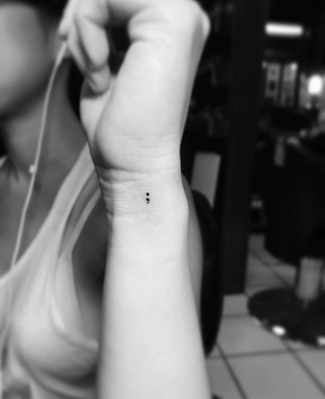 Semicolon tattoo on the inner wrist of a person in black and white.