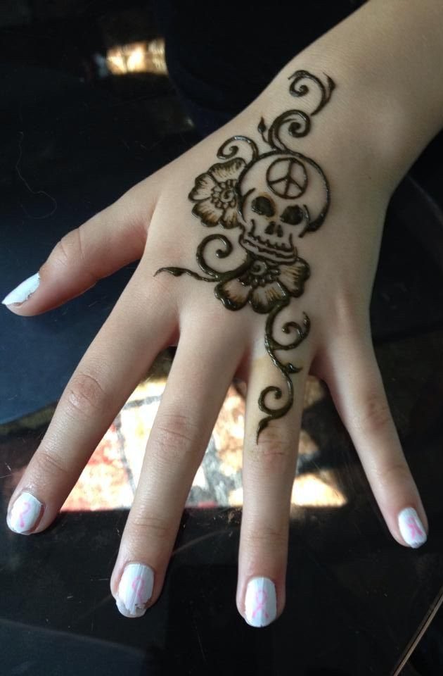 Henna tattoo of a skull with a peace sign and flowers on a hand
