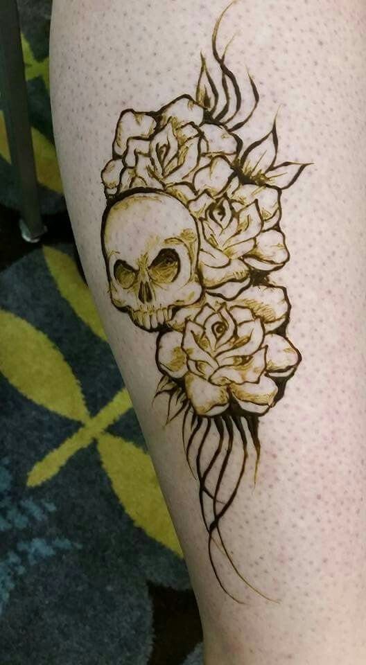 Henna tattoo of a skull entwined with roses on a person's leg