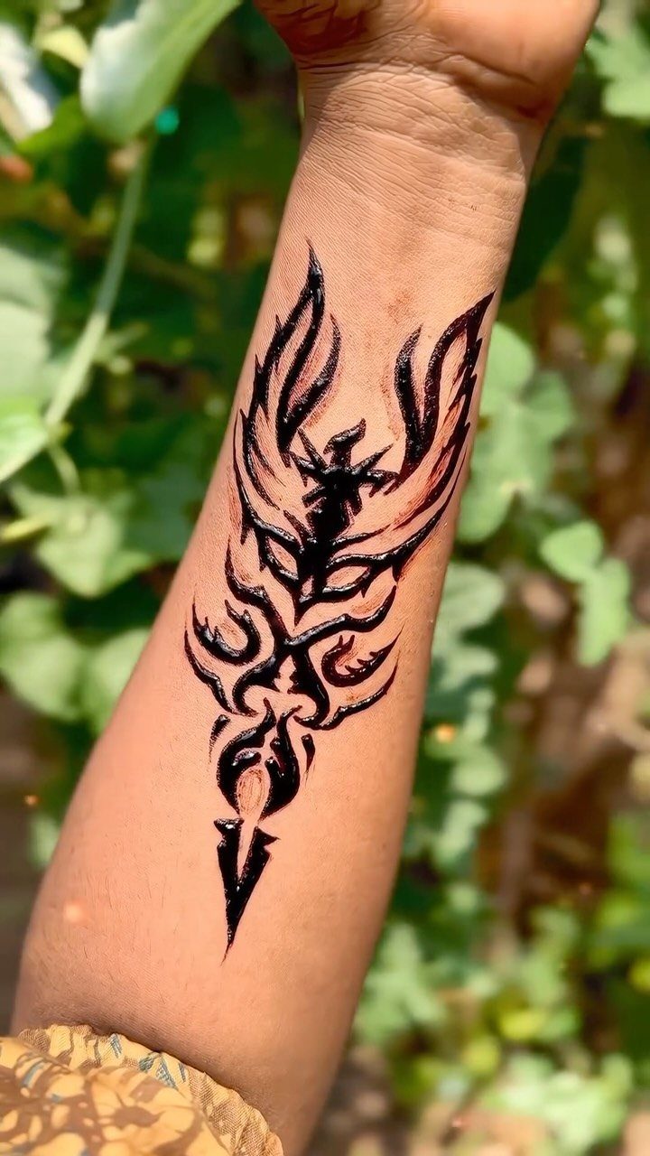 Tribal henna tattoo of a stylized bird on a person's forearm.