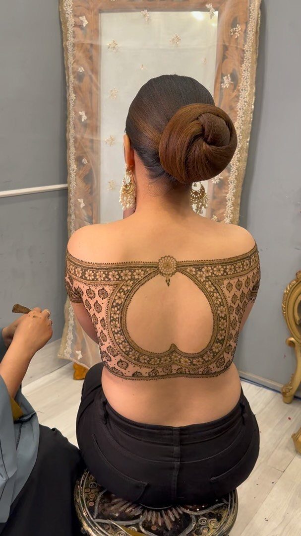Woman with intricate brown henna tattoo patterns across her upper back and shoulders.