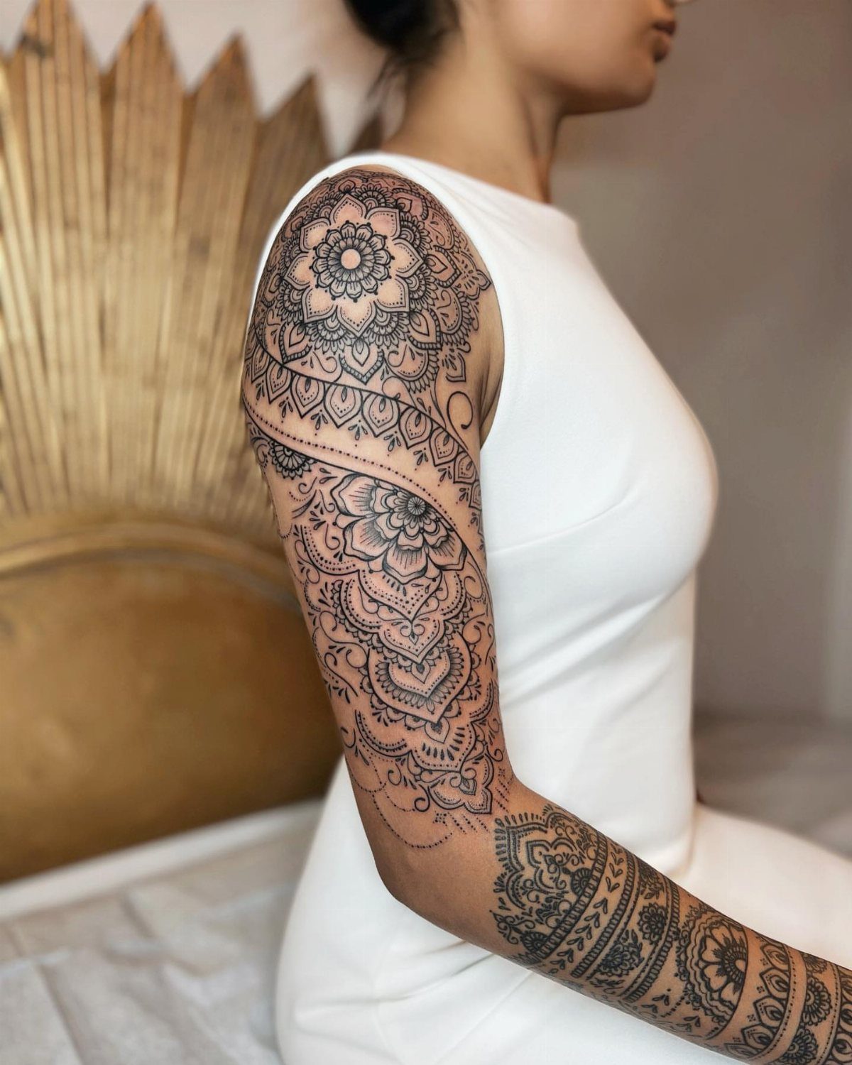 Intricate black henna tattoo designs covering a person's shoulder and arm in floral patterns.