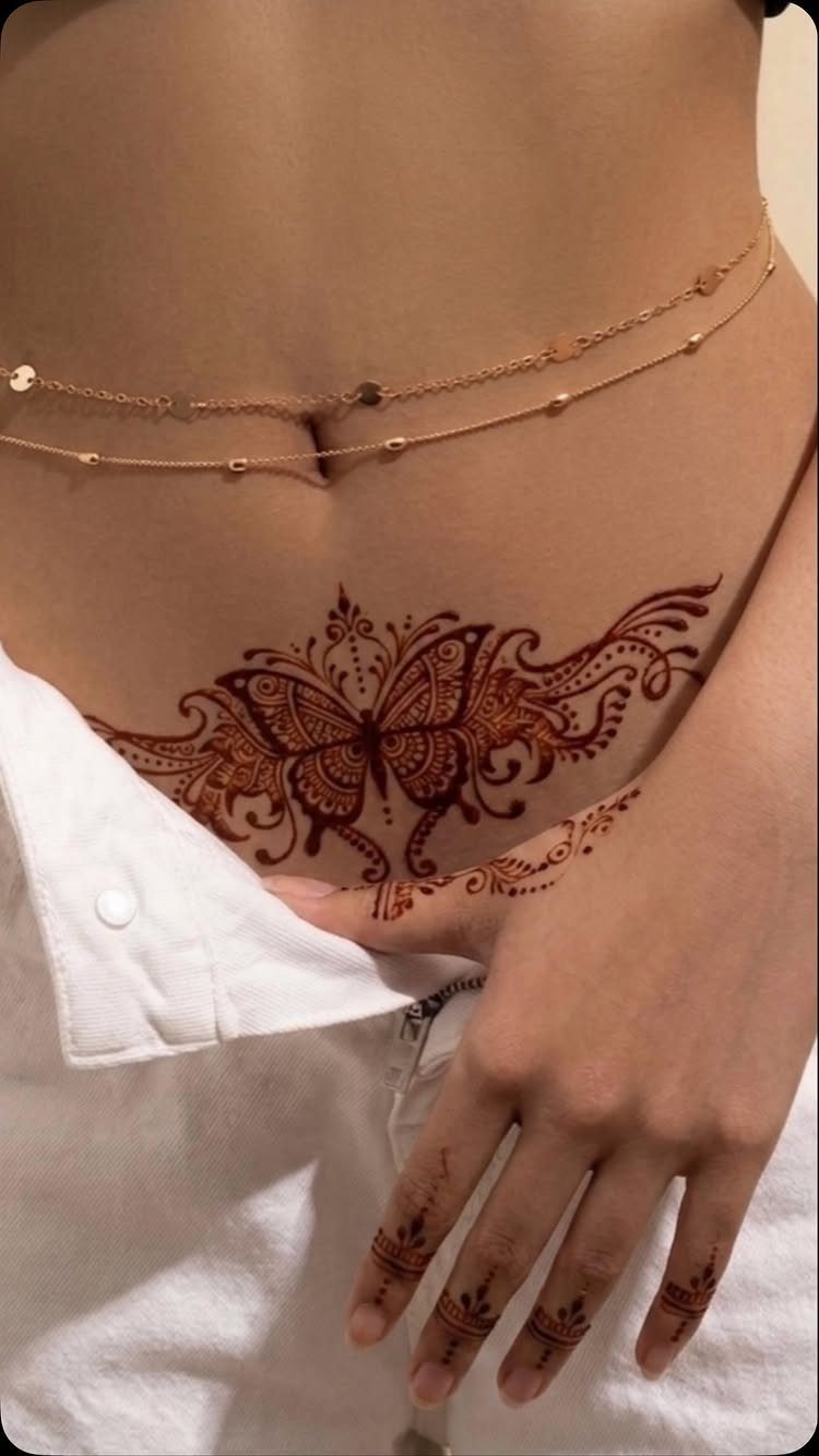 Henna tattoo of a butterfly on a stomach and patterns on fingers