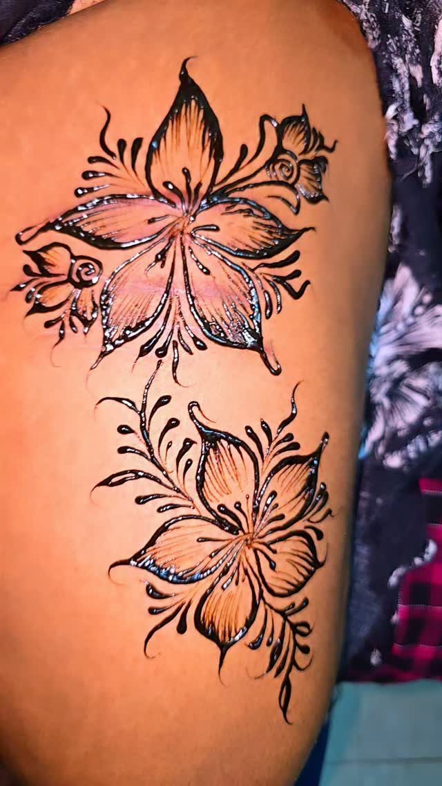 Two floral henna tattoo designs with dark brown outlines on a person's skin.