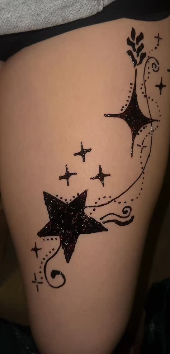 Henna tattoo on a leg featuring stars and swirling decorative lines.