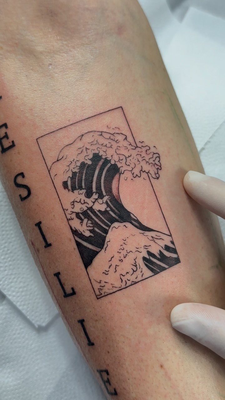 Ocean wave tattoo with thick and thin black lines inside a rectangular frame.
