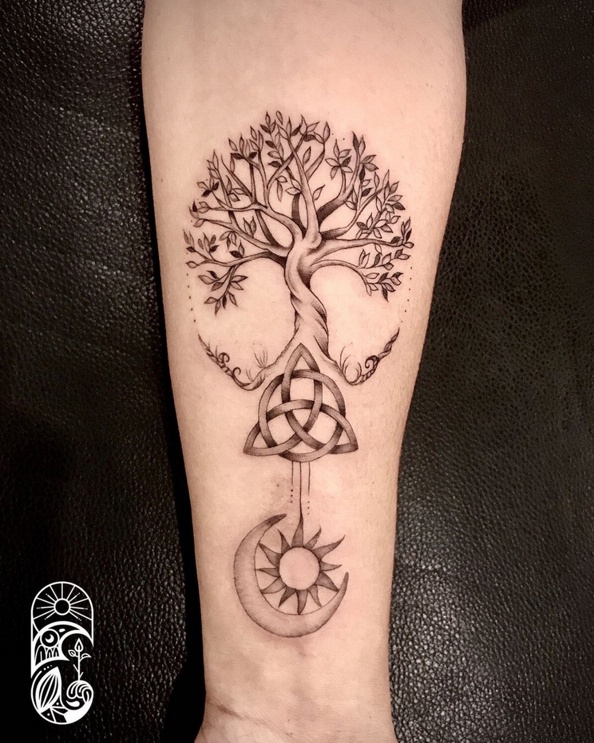Tree tattoo with a Celtic knot and moon sun symbol on a forearm