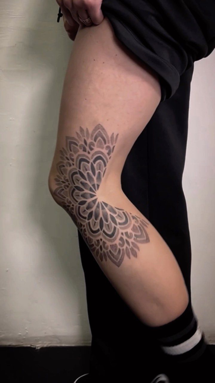 Mandala tattoo with geometric patterns centered on a person's knee and leg.