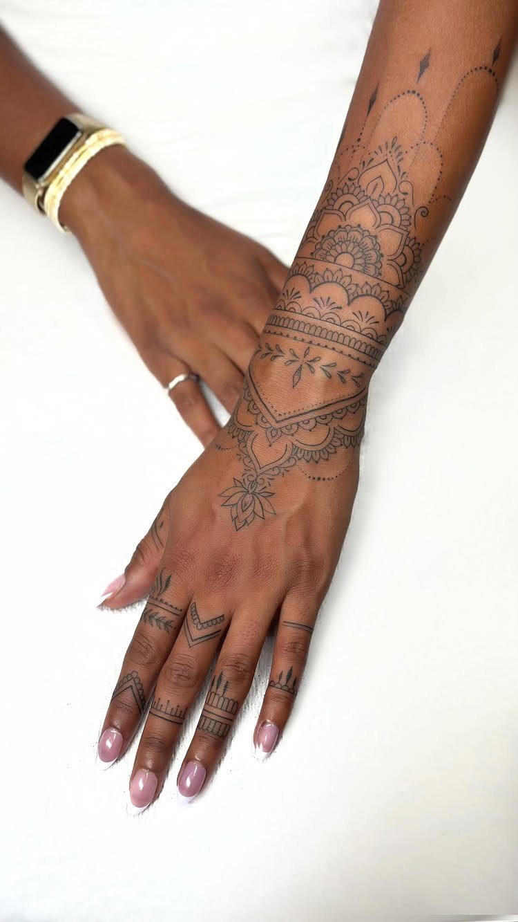 Intricate black mandala tattoo covering the hand, wrist, and forearm of a person.