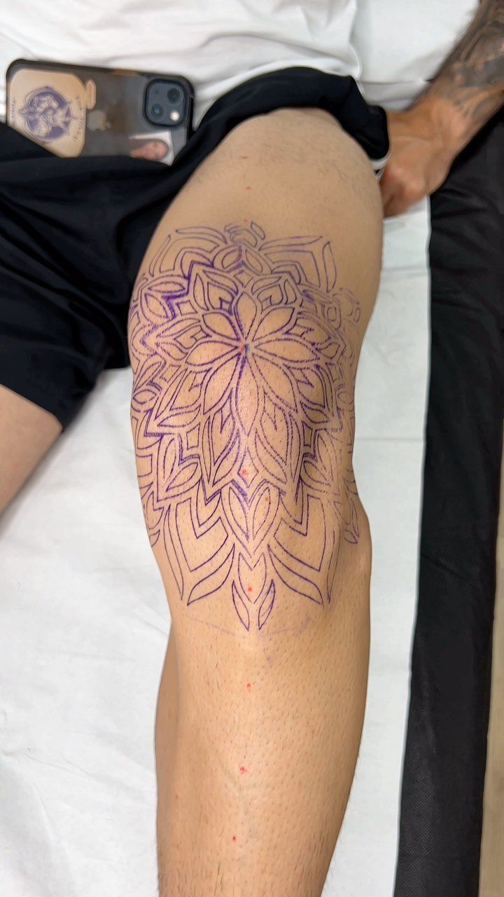 Purple mandala tattoo stencil applied to a person's knee on a white surface