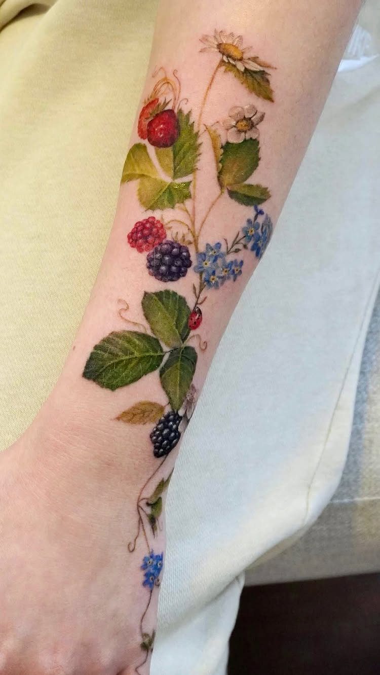 Realistic tattoo of berries and flowers on a person's forearm with detailed green leaves.