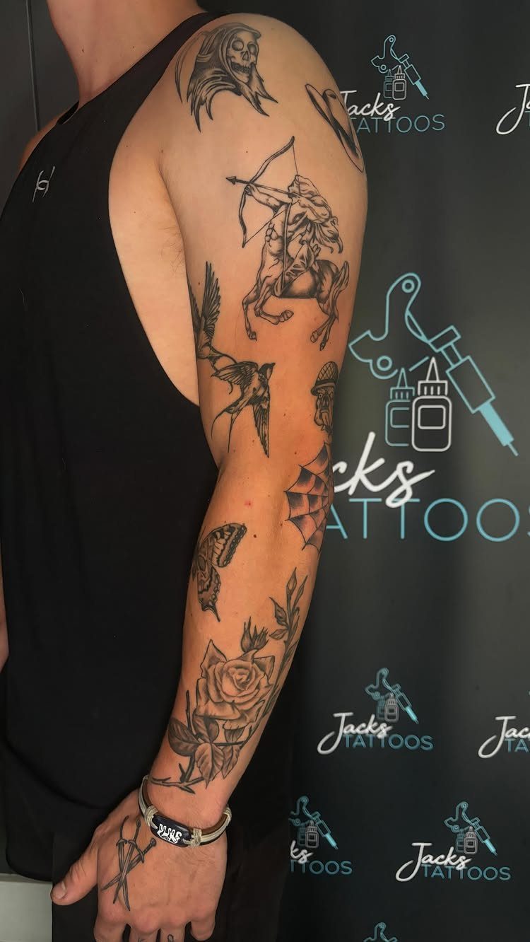 Arm with various black ink patchwork tattoos including a centaur and a rose.