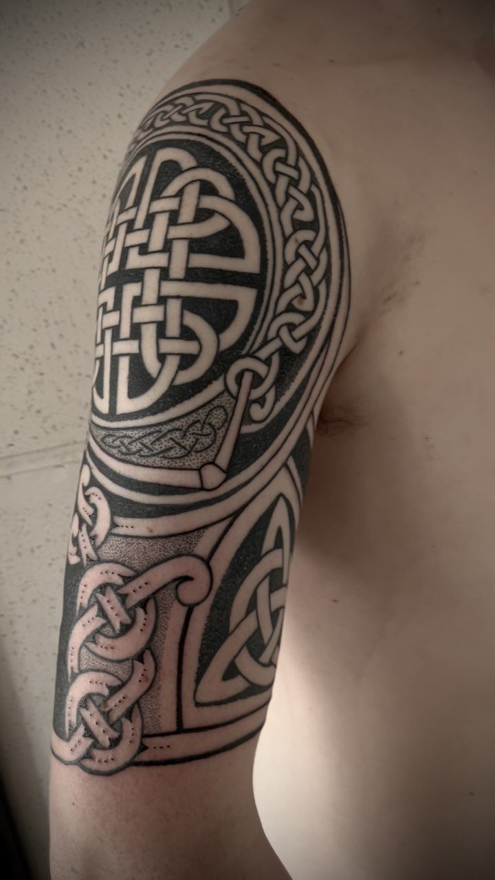 Celtic knot tattoo with interlocking black ink patterns on a person's upper arm