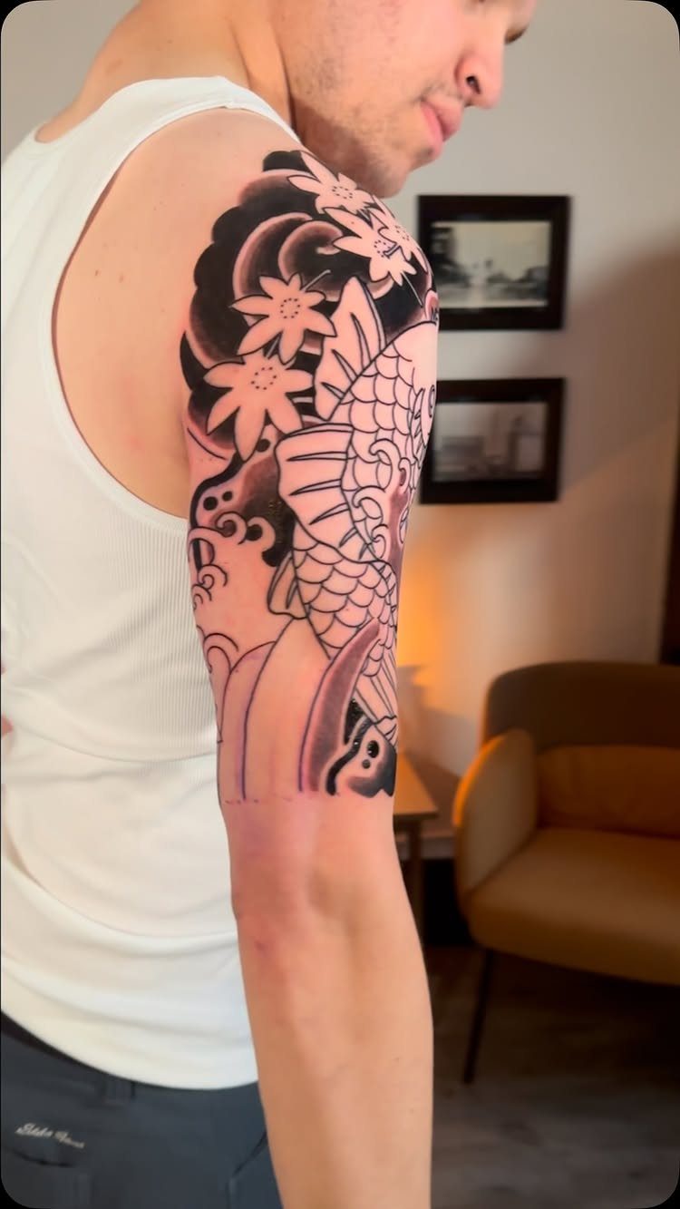Japanese koi fish and cherry blossom tattoo on a man's upper arm