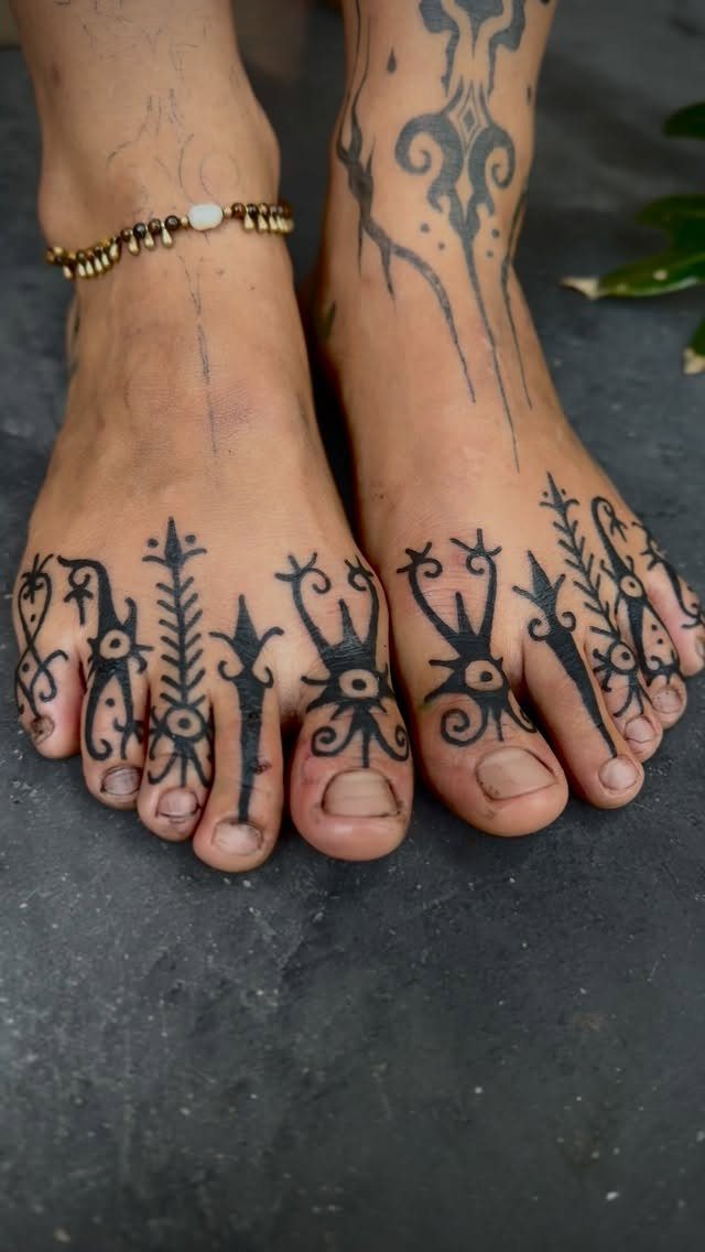 Feet with bold black tribal tattoos on the toes and ankles.