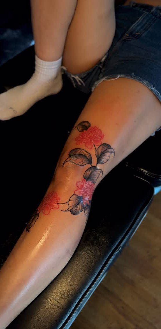 Red and black floral tattoo on a person's lower leg
