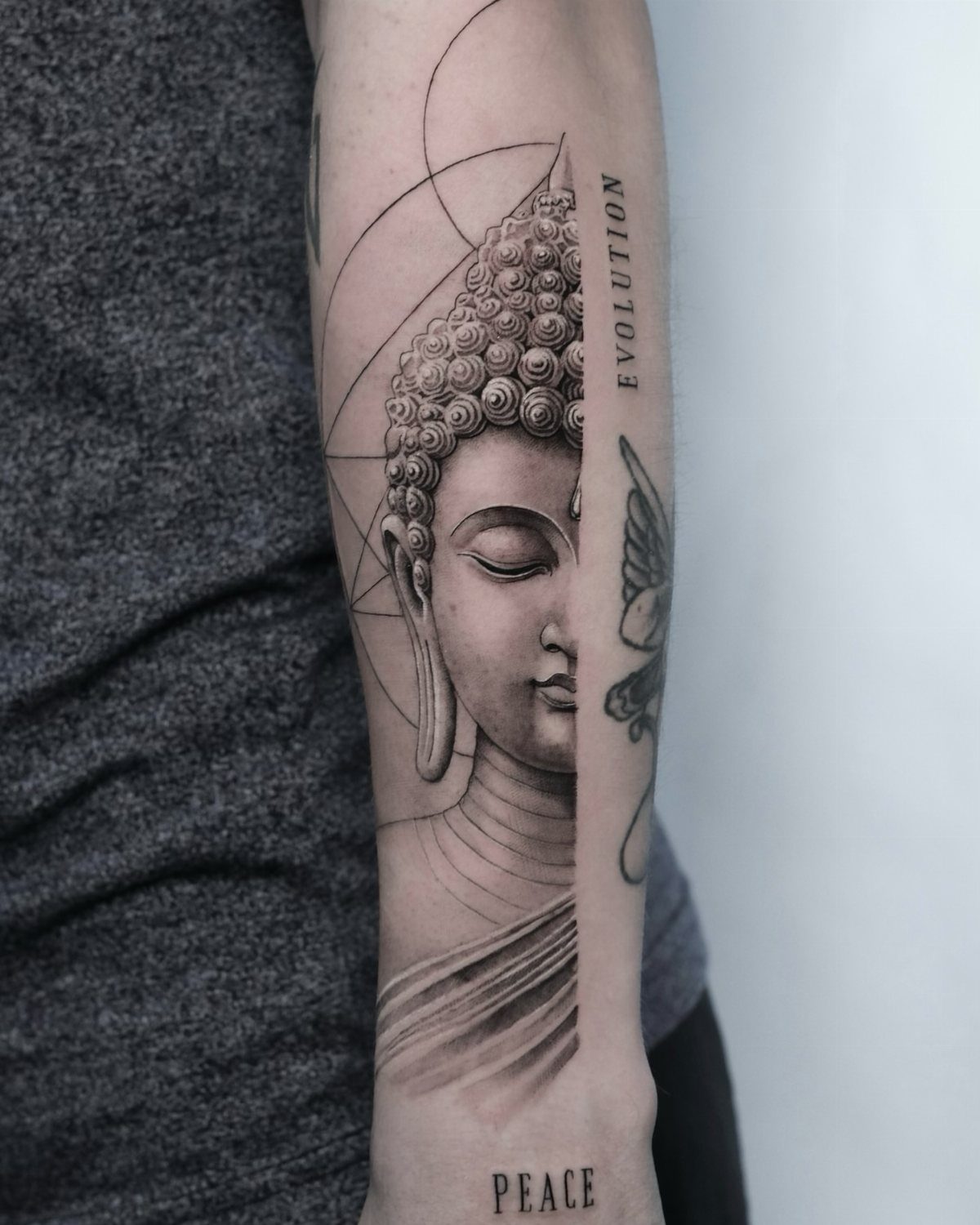 Buddha tattoo on a forearm with geometric lines and the words evolution and peace