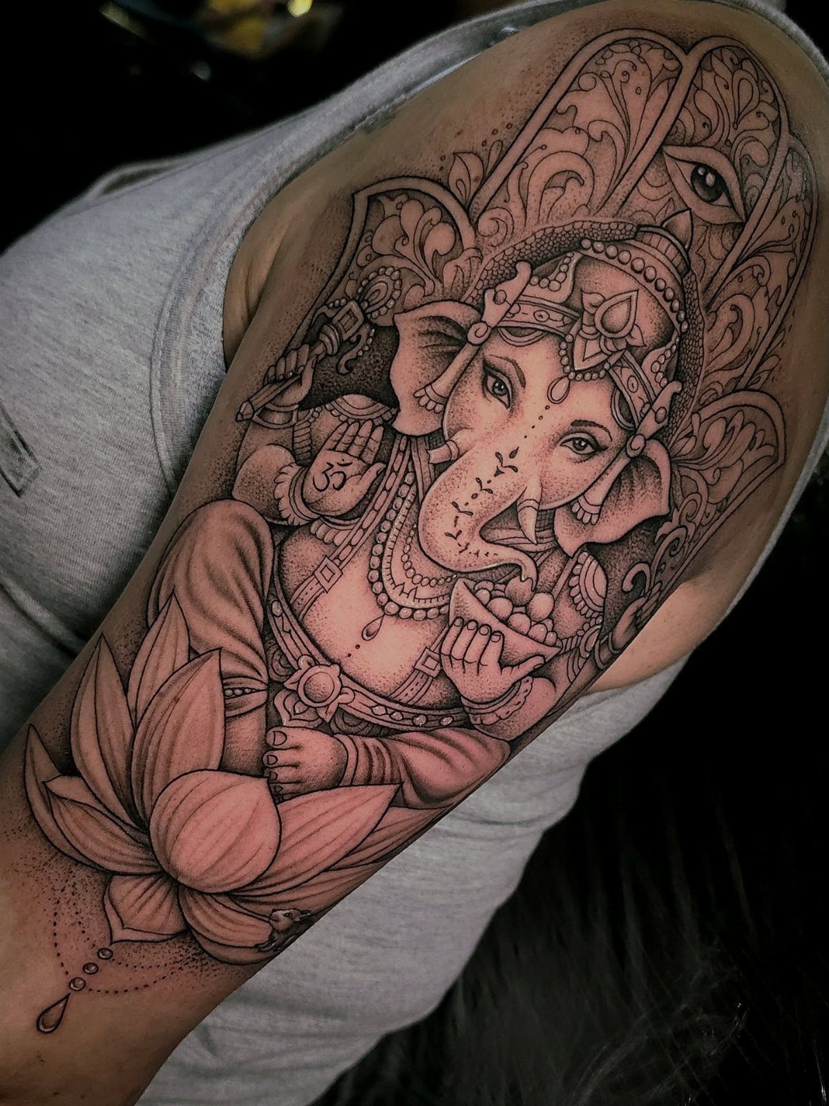 Ganesha tattoo on an upper arm featuring a lotus flower and ornate patterns