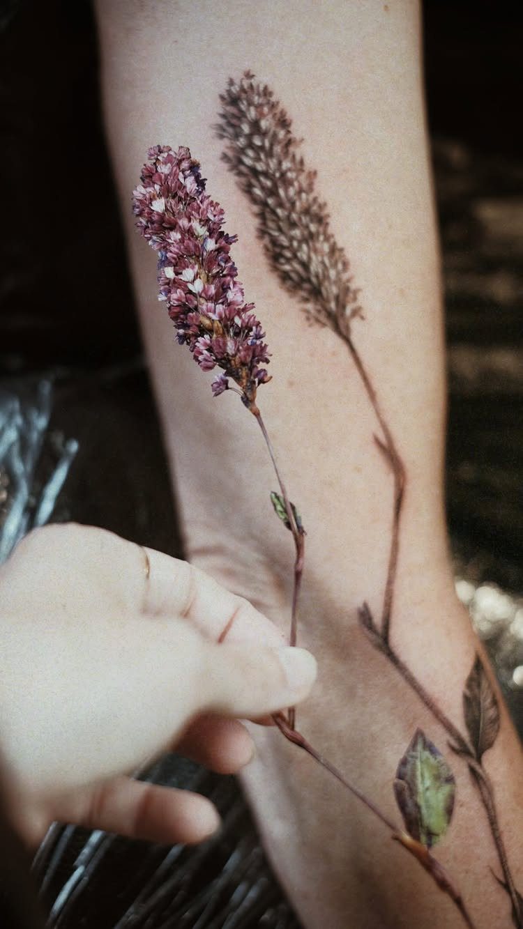 Detailed botanical tattoo of purple flowers and seed heads on a person's leg.