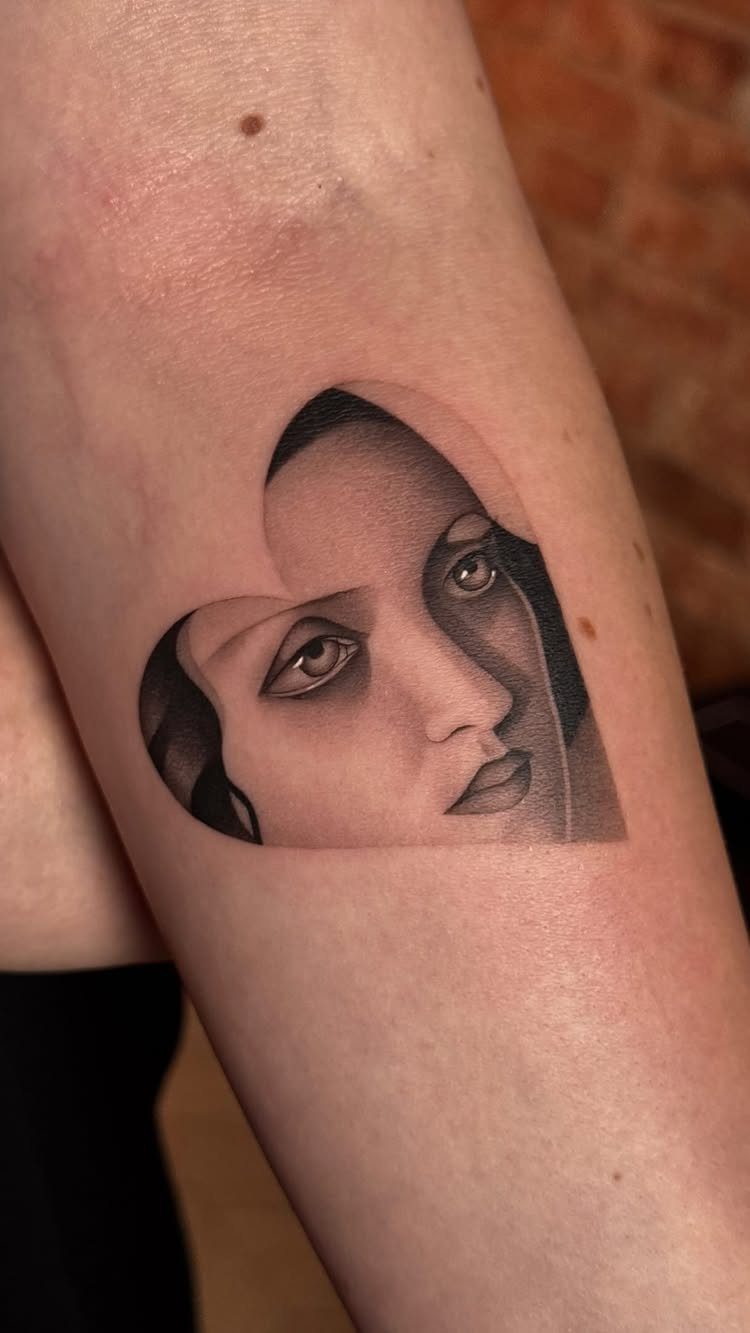 Woman's face tattoo in black and grey ink on a person's arm.