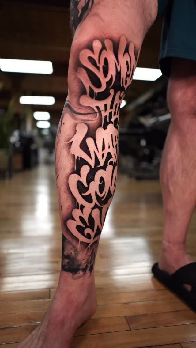 Stylized black ink tattoo with negative space lettering on a person's lower leg.